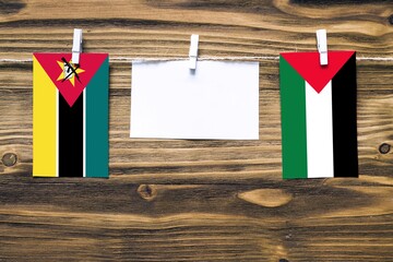 Hanging flags of Mozambique and Palestine attached to rope with clothes pins with copy space on...
