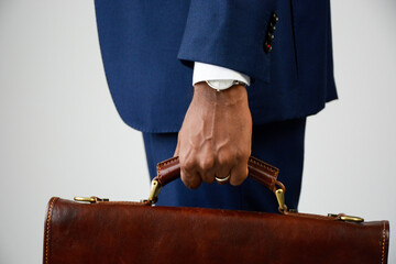 Close up of stylish young businessman in formal wear holding briefcase. Man in blue business suit....
