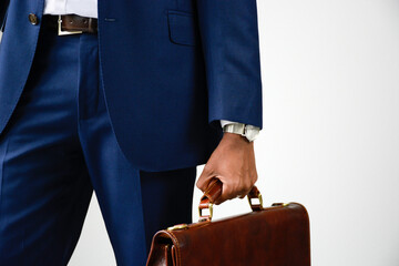 Close up of stylish young businessman in blue formal wear holding briefcase. Business suit. Front...
