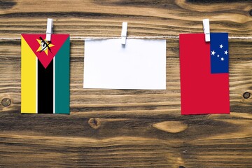 Hanging flags of Mozambique and Samoa attached to rope with clothes pins with copy space on white...