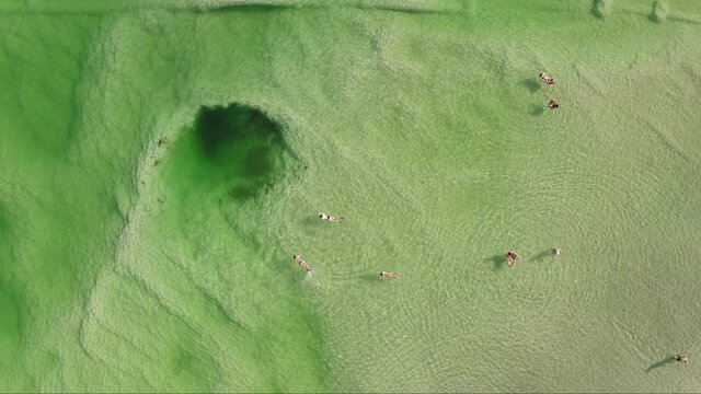 People Floating And Swimming Next To A Giant Sinkhole In The Dead Sea, Israel.