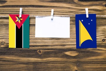Hanging flags of Mozambique and Tokelau attached to rope with clothes pins with copy space on white...
