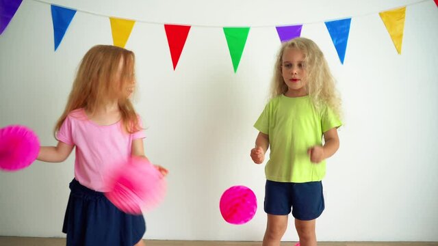 Girls pretending cheerleaders holding pink pompon paper balls. camera motion