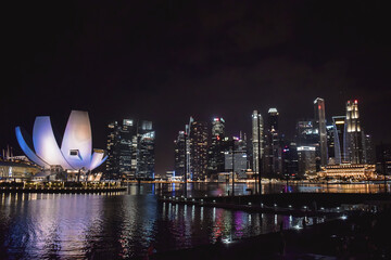 Singapore skyline with the ArtScience Museum with night lights reflected in the water of the bay