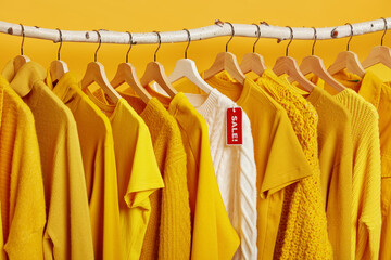 Clearance sale in clothes store. Yellow and bright clothing on hangers during Black Friday. Big...