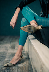 young stylish woman in colorful leggins and leather jacket sitting on black bed sheet