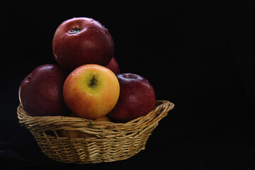 red apples in a wicker basket on a black background. Concept - healthy eating, diet, autumn