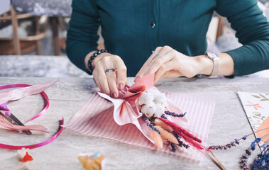 female hands make a bouquet of dried flowers. selective focus. master class of floristry