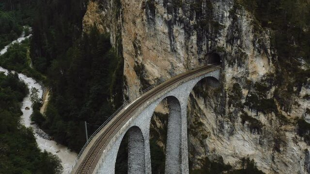 Aerial close-up shot of famous Landwasser Viaduct bridge tunnel entrance, epic travel destination in Switzerland Alps.