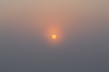 Shot of sun raising in haze over cloudless sky at early morning