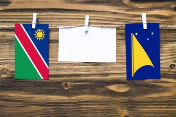 Hanging flags of Namibia and Tokelau attached to rope with clothes pins with copy space on white note paper on wooden background.Diplomatic relations between countries.