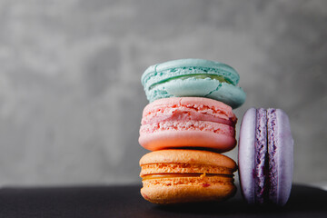 Colorful turquoise, pink, orange, purple cake French macaron or macaroon on concrete gray background
