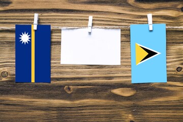 Hanging flags of Nauru and Saint Lucia attached to rope with clothes pins with copy space on white...