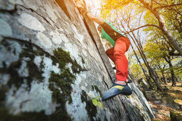 Fototapeta premium A free aged male climber hangs on a rock wall in a forest in the mountains. Mature Sports Concept
