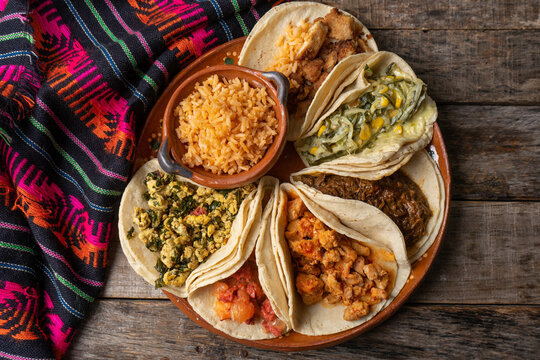 Mexican stew tacos also called "guisados" with rice on wooden background