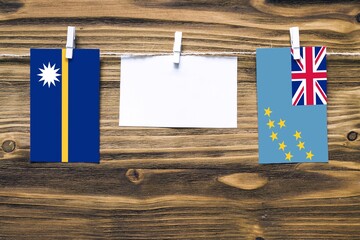 Hanging flags of Nauru and Tuvalu attached to rope with clothes pins with copy space on white note...