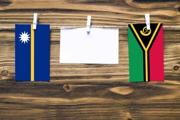 Hanging flags of Nauru and Vanuatu attached to rope with clothes pins with copy space on white note...