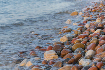 Fototapeta na wymiar azure waves on a stony beach under the sun