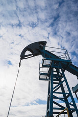 Oil pump on the background of blue sky and the morning sun, sun glare on the oil pump