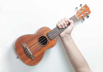 Hand grabbing a wooden ukulele. White background.