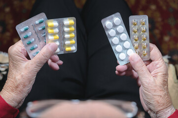 Closeup of a tablet on the hands of an old woman. The concept of choosing medication in old age