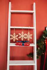 Christmas decor, white staircase, three snowflakes and a gift on the step against a red wall