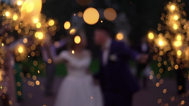 Abstract blur. People light sparklers on the street. Celebration of wedding. Romantic evening or night with lights. Bride and groom