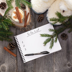 Planning new year. Notebook with to do list, Christmas tree branches and pinecones on wooden...