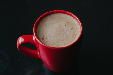 red cup with mokachino coffee in a cafe on a dark background