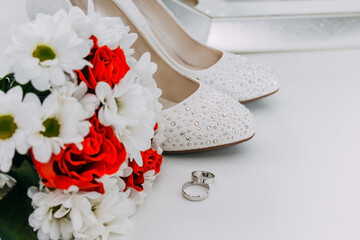 Wedding decor, details of the morning of the bride. White shoes in rhinestones and wedding rings