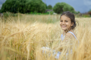 Beauty little girl outdoors enjoying nature wheat field.