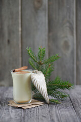 Homemade eggnog with cinnamon for Christmas and winter holidays on wooden table.