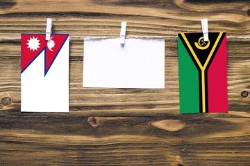 Hanging flags of Nepal and Vanuatu attached to rope with clothes pins with copy space on white note...
