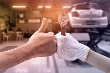 Mechanic hand checking and fixing a broken car in  garage.hand of mechanic with thumbs up and tool