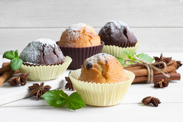 Handmade muffins with a leaf of mint on a wooden table with cinnamon and star anise