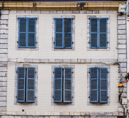 Six windows with blue shutters in a stone wall