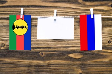 Hanging flags of New Caledonia and Russia attached to rope with clothes pins with copy space on...