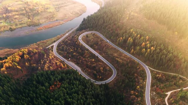 Flight over the autumn mountains with mountain road serpentine, river and forest. Ukraine, Carpathian mountains