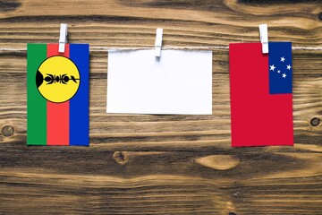 Hanging flags of New Caledonia and Samoa attached to rope with clothes pins with copy space on...