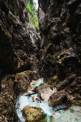 Exploring the beauty of Höllentalklamm / Hell Valley Gorge near Grainau during a moody summer day with a clear water stream (Höllental, Germany, Europe)