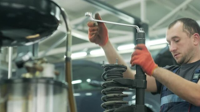Auto car mechanic working on car shock absorber in car service workshop