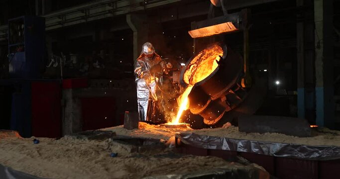 Hard work in a foundry. Metal smelting furnace in steel mill. Molten metal pouring, metallurgy, steel casting foundry. Steel manufacturing