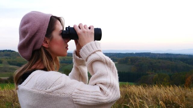 Style girl with binoculars at countryside with mountains on background