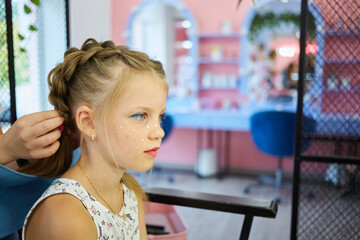 Hairdressing services. Reating hairstyle. Hair styling process. Children hairdressing salon