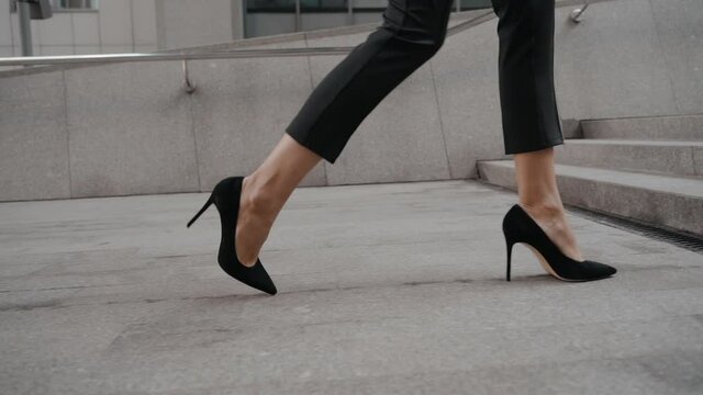 Young adult businesswoman in high-heels walking on stairs