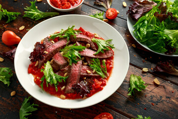 Beef Steak with Romesco sauce, nuts and vegetables on white plate