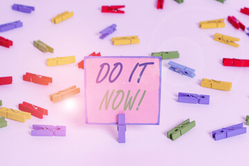 Text sign showing Do It Now. Business photo text not hesitate and start working or doing stuff right away Colored clothespin papers empty reminder white floor background office