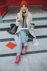 Young woman sitting on stairs with coffee to go