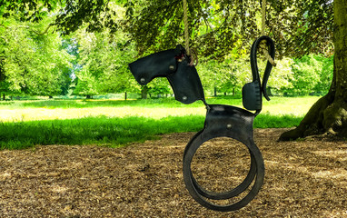 Recycled garden swing hanging from a tree over wood chippings. Re-modelled into the shape of a horse from an old car tyre. Well used but currently unoccupied. Countryside background. England - 300001718