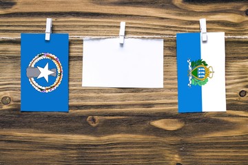 Hanging flags of Northern Mariana Islands and San Marino attached to rope with clothes pins with...